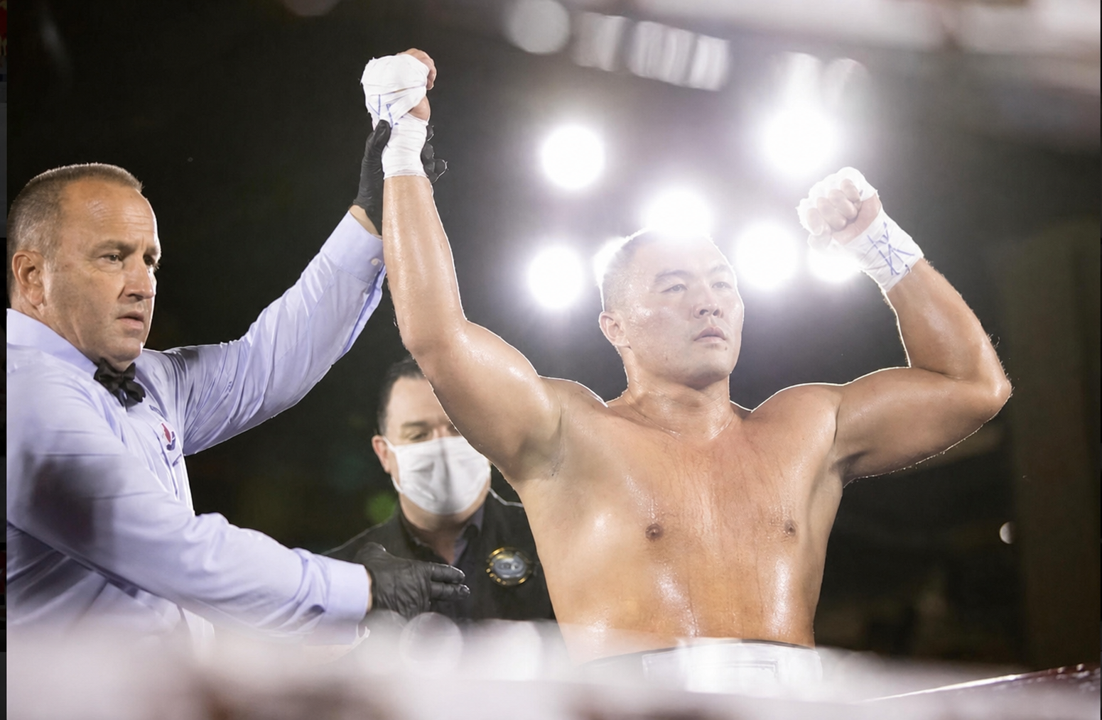 Referee raising Serik Musadilov's hand in victory after a win